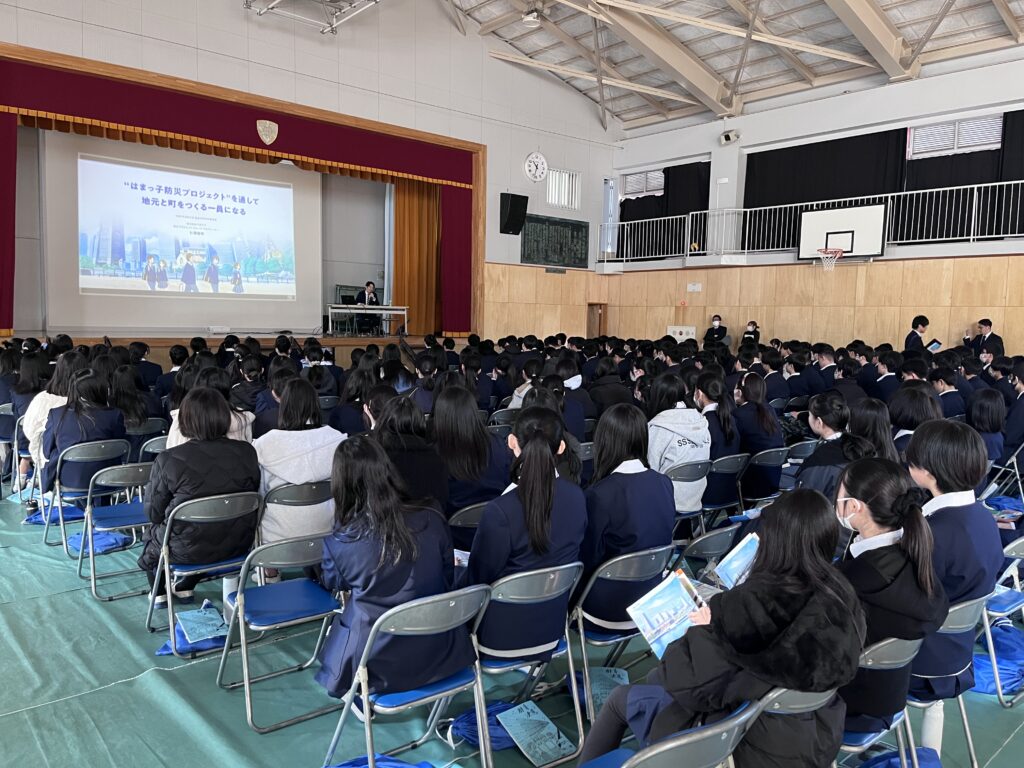 体育館内で卒業講演の始まりを待つ中学生たち