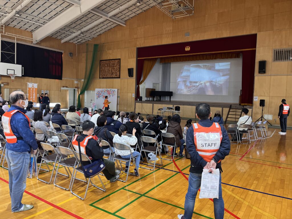 体育館にて防災アニメを見るイベント参加者たち